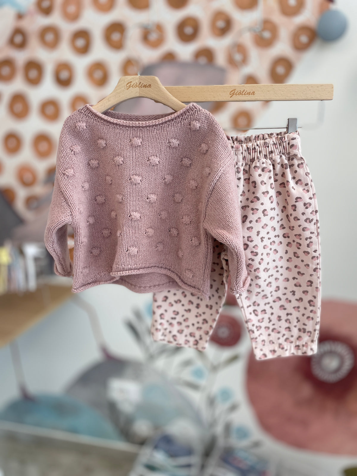 Pullover rosa con pompom pantalone maculato e t-shirt con colletto